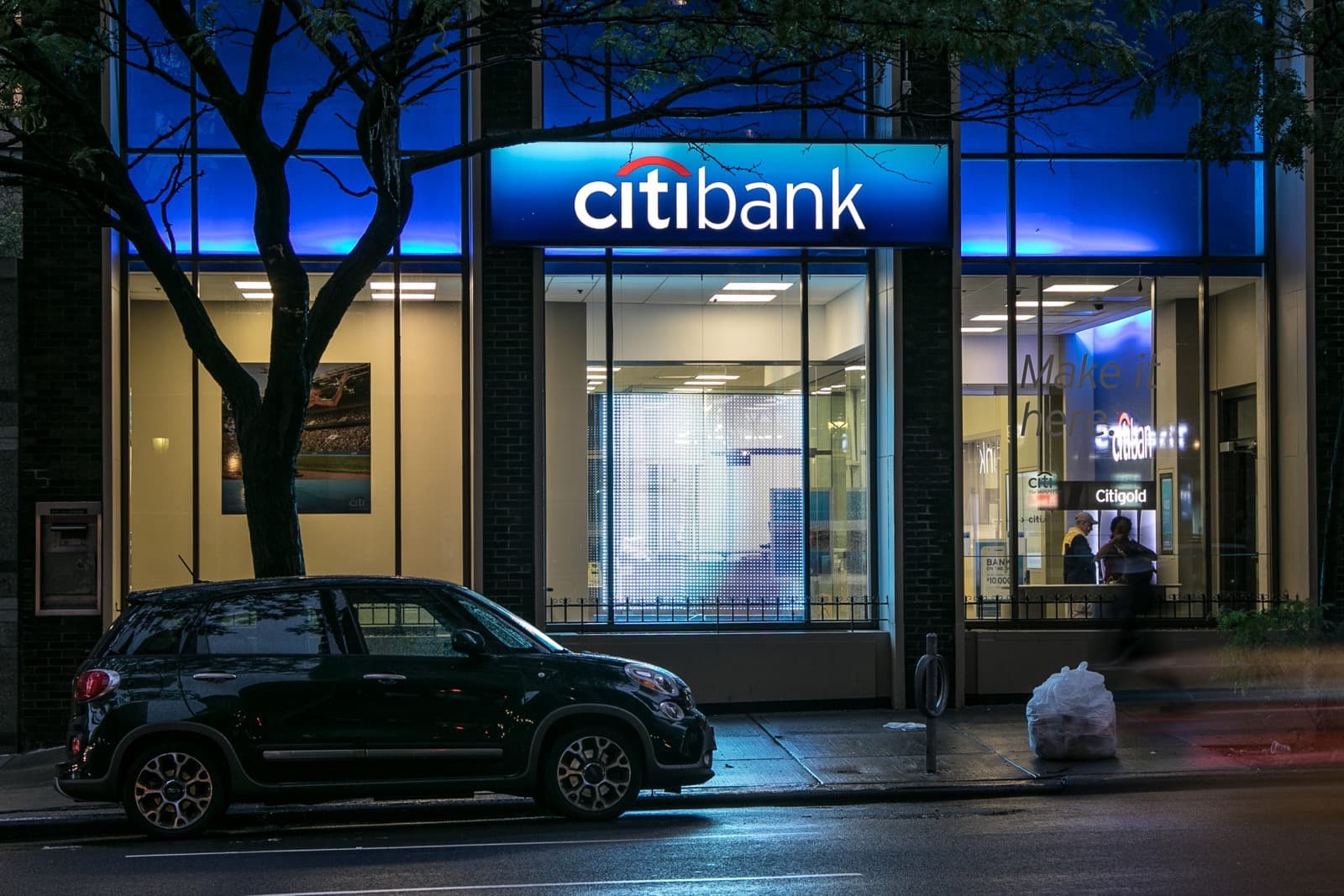Citibank branch at night with the illuminated storefront sign.